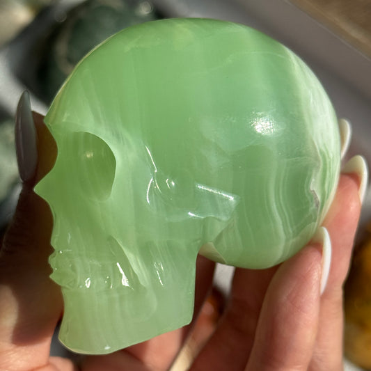 Skull Carving - HQ Green Onyx, side view showing translucent bright green coloring and pale bands.