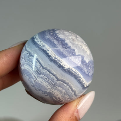 Blue Lace Agate Sphere #2, held in hand, showing blue and white wavy bands.