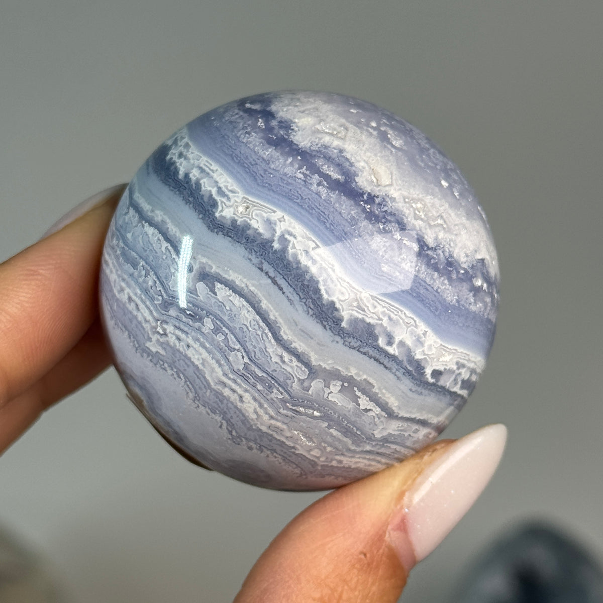 Blue Lace Agate Sphere #3, held in hand, showing blue and white banding.