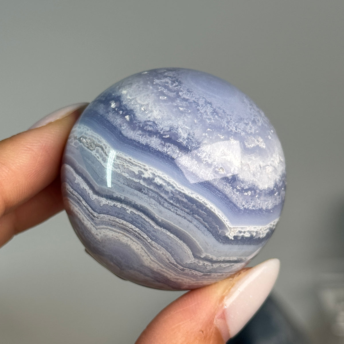 Blue Lace Agate Sphere #5, held in hand, showing blue and white banding.
