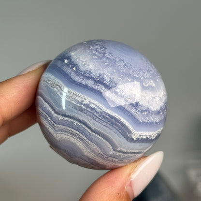 Blue Lace Agate Sphere #5, held in hand, showing blue and white banding.