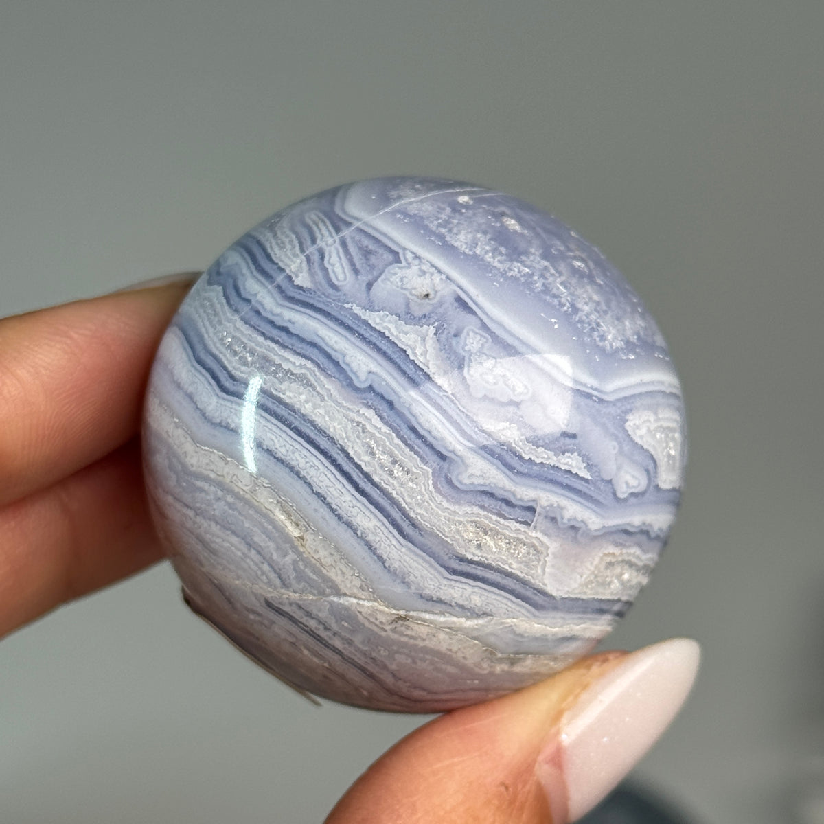 Blue Lace Agate Sphere #8, held in hand, showing blue and white layered bands.