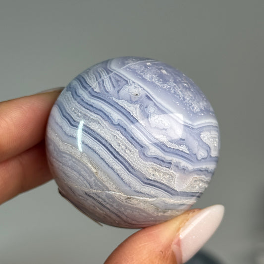 Blue Lace Agate Sphere #8, held in hand, showing blue and white layered bands.