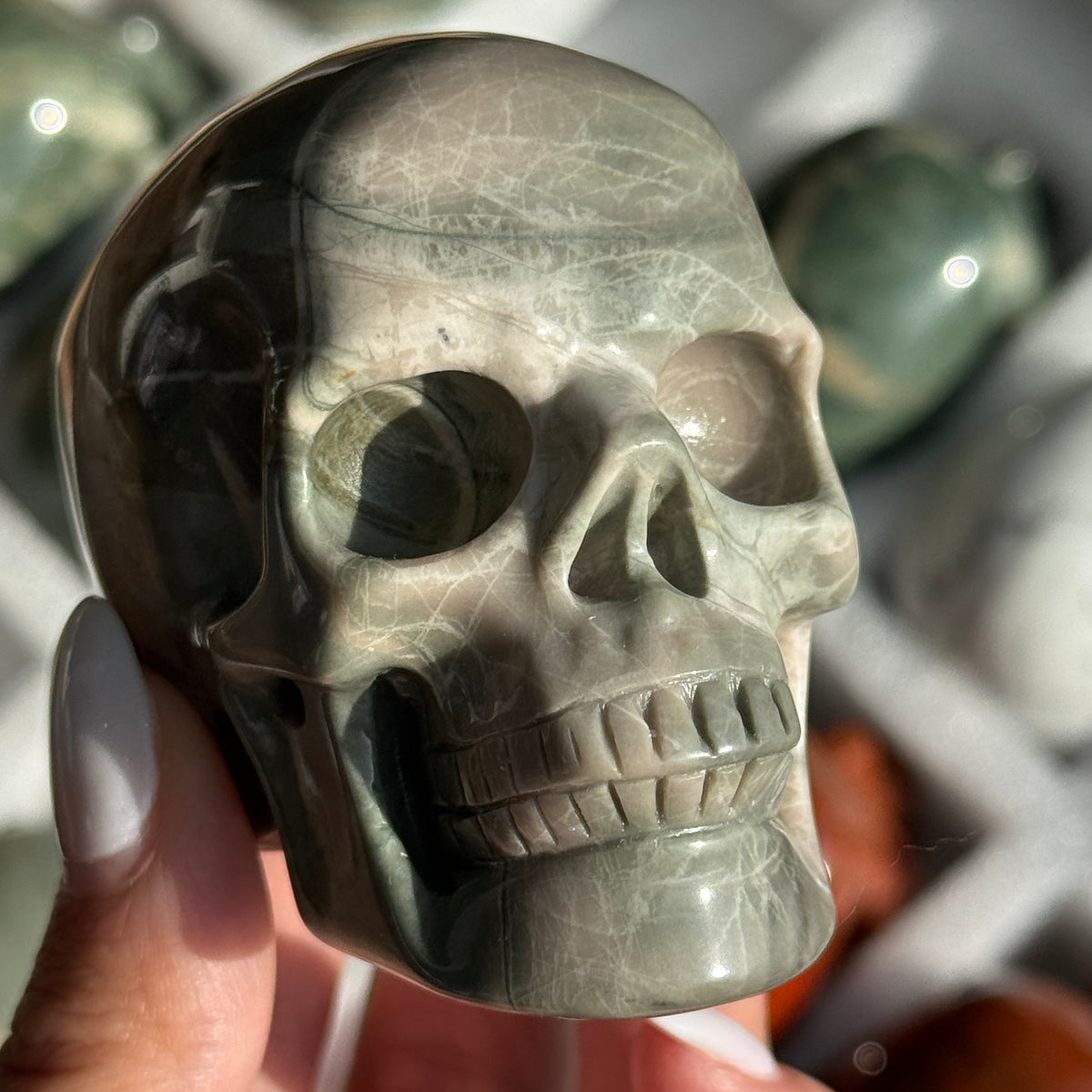Skull Carving - Green Dragon Jasper #1, front view showing gray-green coloring with broad pale bands.