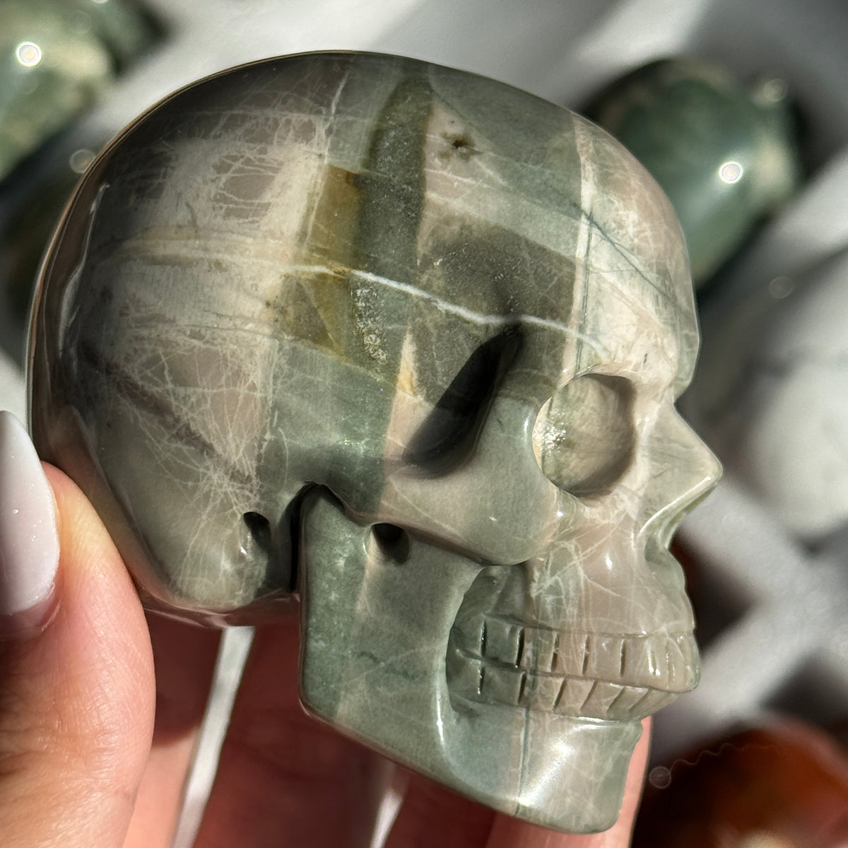 Skull Carving - Green Dragon Jasper #1, side view showing gray-green coloring with broad pale bands.