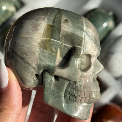 Skull Carving - Green Dragon Jasper #1, side view showing gray-green coloring with broad pale bands.