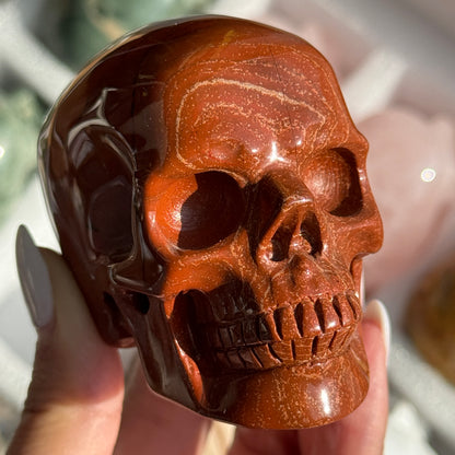 Skull Carving - Red Jasper #14, front view showing rust-red coloring with fine dark veins.