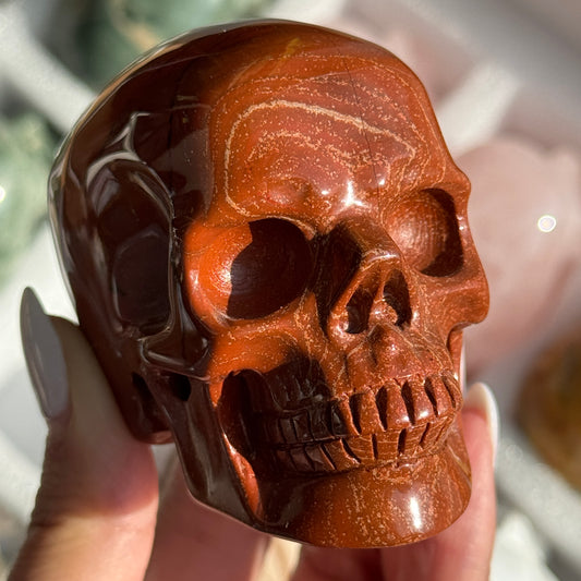 Skull Carving - Red Jasper #14, front view showing rust-red coloring with fine dark veins.