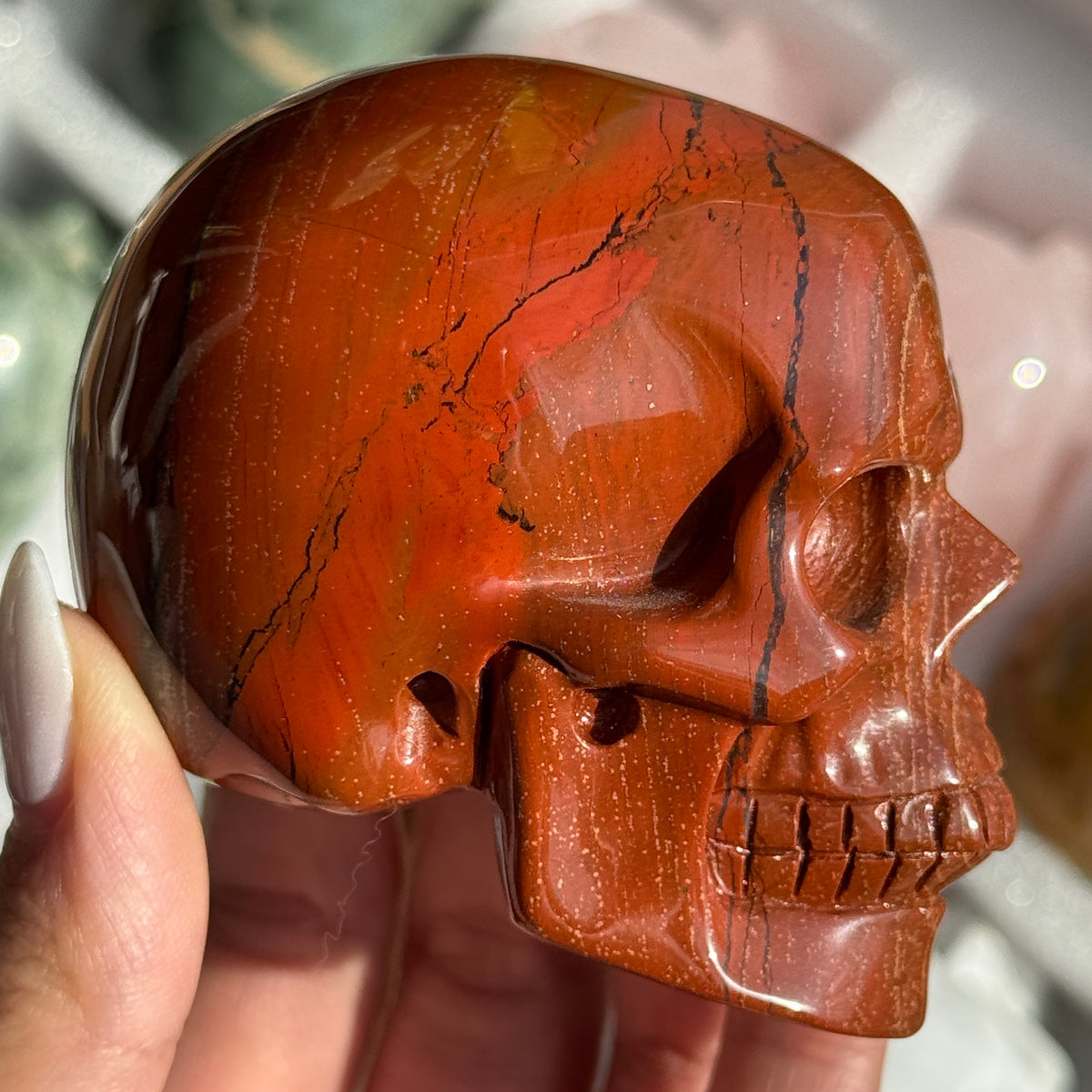 Skull Carving - Red Jasper #14, side view showing rust-red coloring with fine dark veins.