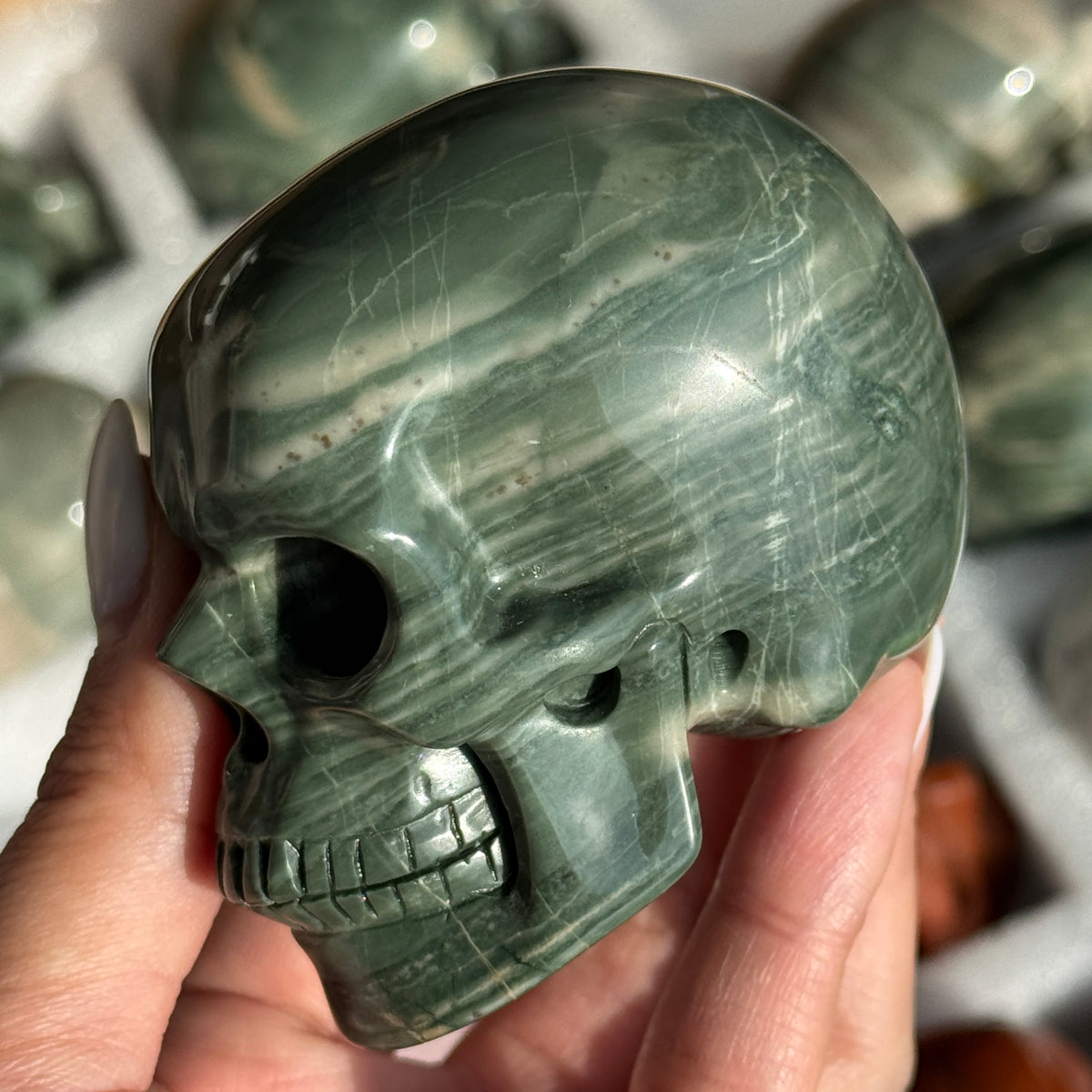Skull Carving - Green Dragon Jasper #4, side view showing dark green coloring and pale curved bands.