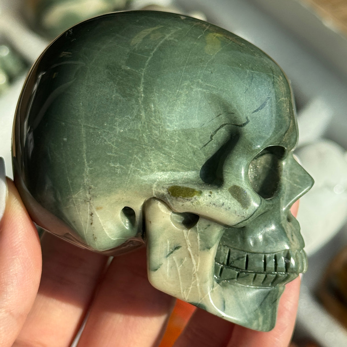 Skull Carving - Green Dragon Jasper #5, side view showing green coloring with cream mineral patches.