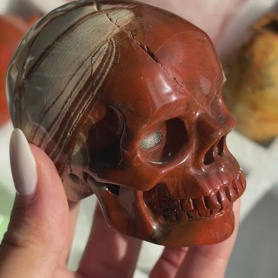 Video of Skull Carving - Red Jasper #15, showing the carved details and rust-red coloring with cream and gray banding.